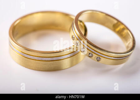 Zwei goldene Hochzeit Ringe auf weiße Oberfläche mit Reflexion Stockfoto