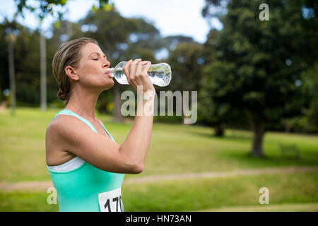 Sportlerin Trinkwasser in Parken auf sonnigen Tag Stockfoto