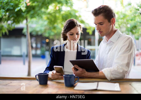 Unternehmer diskutieren über digital-Tablette am Zähler in CafÃƒÂ © Stockfoto