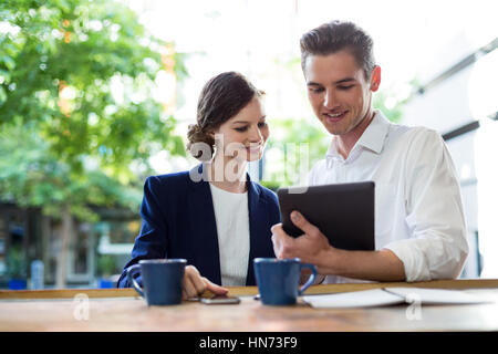 Unternehmer diskutieren über digital-Tablette am Zähler in CafÃƒÂ © Stockfoto