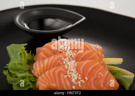 Nahaufnahme von vier Sashimi Sushi mit Sojasauce in schwarze Platte serviert Stockfoto