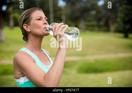 Sportlerin Trinkwasser in Parken auf sonnigen Tag Stockfoto