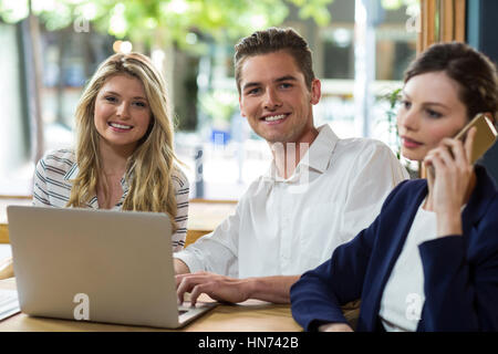 Glückliche junge Freunde, die mit Laptop in CafÃƒÂ © Stockfoto