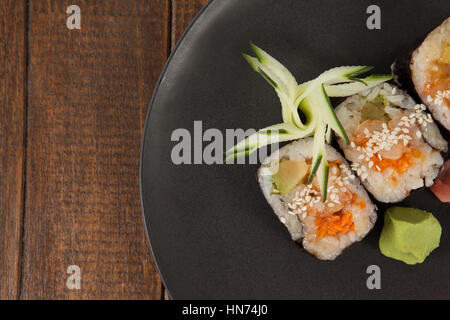 Drei Maki Sushi serviert in schwarz Runde Platte auf Holztisch Stockfoto