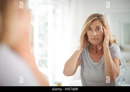 Frustriert senior Frau betrachten Spiegel im Badezimmer Stockfoto