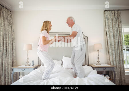 Gerne älteres paar tanzen auf Bett im Schlafzimmer Stockfoto