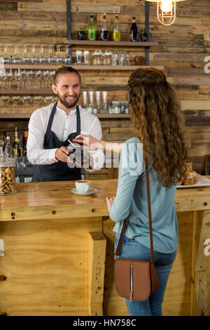 Frau, die Zahlung der Rechnung durch Smartphone mit NFC-Technologie im café