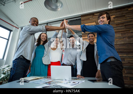 Team von Grafikern geben hohe fünf miteinander im Büro Stockfoto