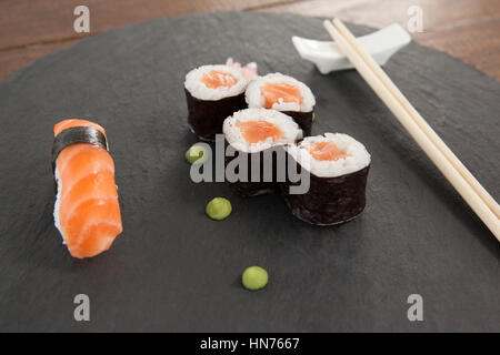 Verschiedene Sushi mit Stäbchen auf grauem Stein Schiefer auf Holztisch serviert-Set Stockfoto