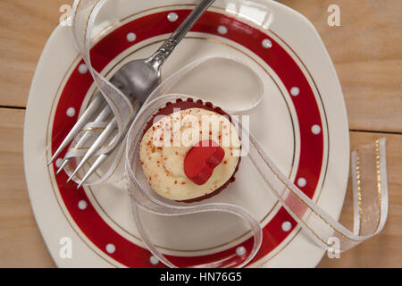 Teller mit leckeren Cupcake verziert mit einer Schleife auf Holztisch Stockfoto
