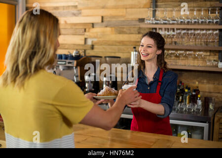 Lächelnde Kellnerin serviert eine Tasse Kaffee an Kunden in CafÃƒÂ © Stockfoto