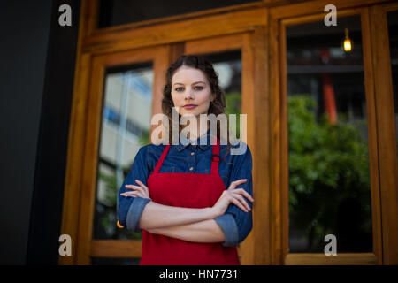 Porträt des lächelnden Kellnerin stehend mit Arme gekreuzt außerhalb der CafÃƒÂ © Stockfoto