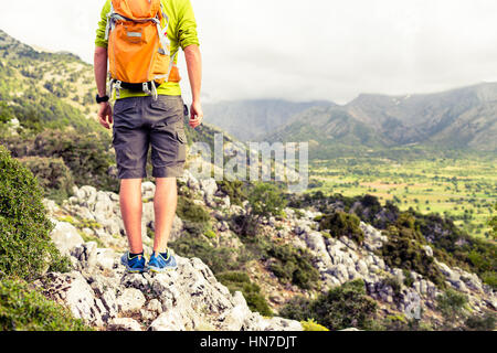 Mann, Blick auf Berge inspirierende Landschaft wandern. Wanderer Wandern mit Rucksack auf felsigen Pfad Wanderweg, einen Blick auf Tal bewundern. Er Stockfoto