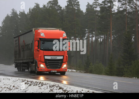 SALO, Finnland - 4. Februar 2017: Orange DAF XF LKW Transporte Sattelanhänger auf nasser Straße an einem nebligen Tag im Winter. Stockfoto