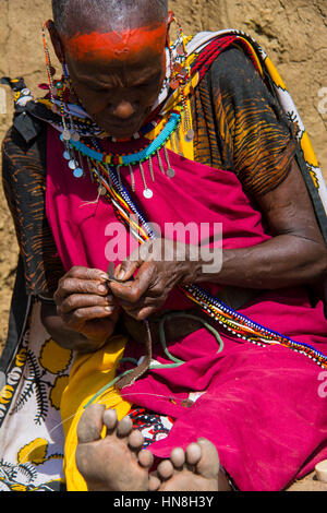 Massai Frau mit Trachtenmode webt Perlen Schmuck in einem Dorf in der Nähe der Masai Mara, Kenia, Ostafrika Stockfoto