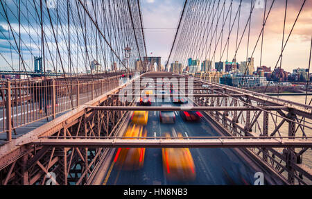 Verkehr auf Brooklyn Bridgeat bewölkten Sonnenuntergang in New York City Stockfoto