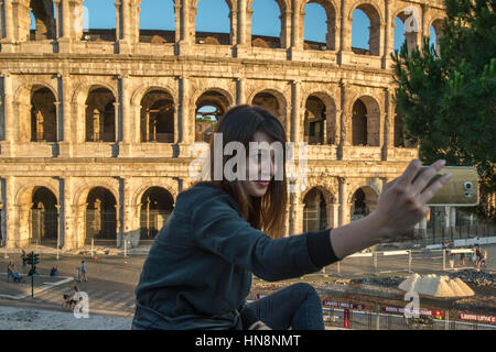 Rom, Italien - junge Frau, die ein Bild von sich selbst mit ihrem Handy vor die berühmte steinerne Amphitheater bekannt als Roman Colosseum finden Stockfoto