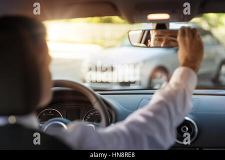 Mann in einem Auto sitzen und Rückspiegel, Fahrzeuginnenraum anpassen Stockfoto