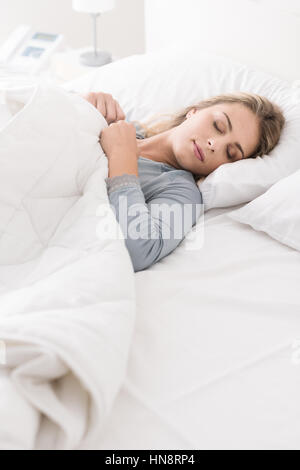 Junge schöne Frau schlafend im Bett, sie ist entspannend und träumen mit geschlossenen Augen, sie deckt sich mit einer weichen Decke Stockfoto