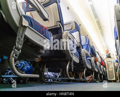 Flight Attendant dient Flugpassagiere bei einem Interkontinentalflug. Niedrigen Winkel Blick hinunter den Gang der Kabine. Stockfoto