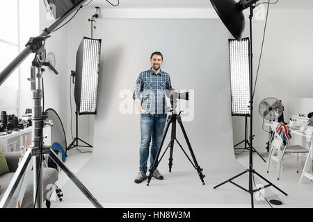 Profi-Fotografen posiert im Studio und mit einer digitalen Kamera, er ist bereit für das Fotoshooting Stockfoto