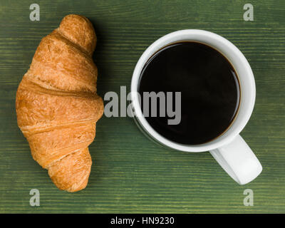 Frisch gebrühten Tasse heißen schwarzen Kaffee mit einem frisch gebackenen Golden Braun Frühstück Croissant bereit, als Flach Ohne Menschen Essen Stockfoto