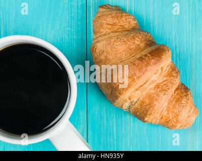 Frisch gebrühten Tasse heißen schwarzen Kaffee mit einem frisch gebackenen Golden Braun Frühstück Croissant bereit, als Flach Ohne Menschen Essen Stockfoto