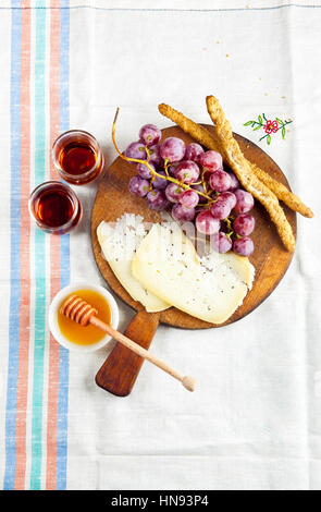 Käse Snack auf einem Holzbrett mit Trauben, Brot-Sticks und italienischer Marsala-Wein. Raum zum Schreiben oder platzieren von Text-Menüs oder Werbung. Stockfoto