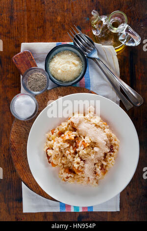 Risotto mit Pfifferlingen in weißer Teller auf einem hölzernen Hintergrund. Ansicht von oben. Stockfoto