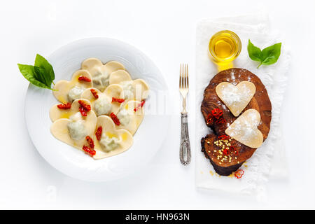 Essen in Herzform. köstlichen Ravioli. frisch hausgemacht. in einem Teller gekocht und roh auf ein Brett aus Olivenholz Stockfoto