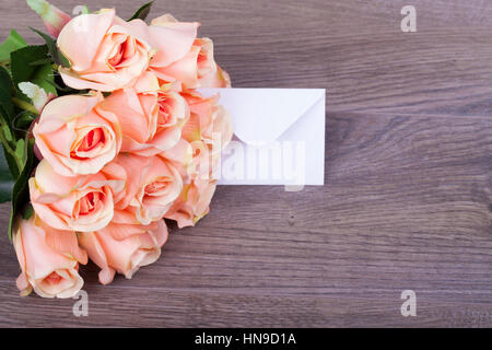 Schöne Rosen mit einer Notiz in den Umschlag auf Holzsockel Stockfoto
