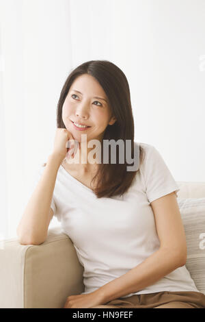 Junge japanische Frau in einem weißen Raum auf dem sofa Stockfoto