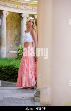 Schöne junge Frau in langen rosa Rock und weißen Oberteil im freien Stockfoto