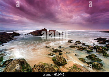 Runrise am Birubi Beach in der Nähe von Anna Bay, NSW, Australien. Bunte Seelandschaft mit Algen bedeckt Felsbrocken und reibungslose Surfen Wasser. Stockfoto