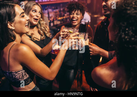Gruppe von Freunden feiern in einem Nachtclub und Toasten Getränke. Glückliche junge Menschen mit Cocktails im Pub. Stockfoto