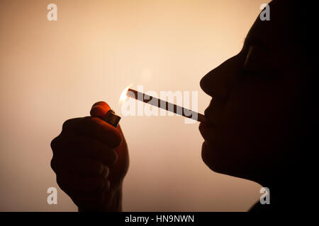 Silhouette einer Frau, die aufleuchten einer Zigarette. Stockfoto