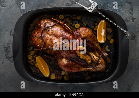 Gebratene Ente mit Orangen und Äpfel in eine Pfanne geben, dunkles Foto, Ansicht von oben Stockfoto