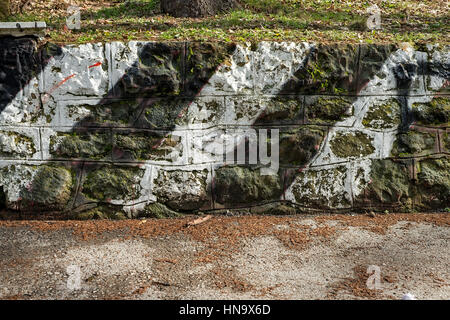 Stützmauer aus Stein mit grünen und weißen Streifen Stockfoto