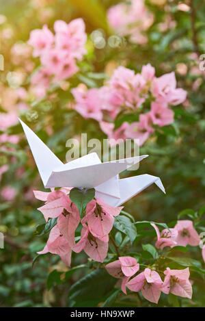 Origami-Weißbuch Schwan auf rosa Blume unscharf Hintergrund Stockfoto