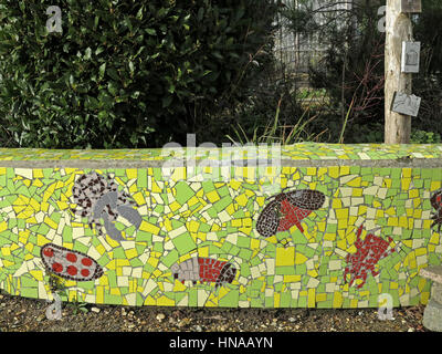 Grüne Mosaik Gartenmauer mit Libellen und Schmetterlingen verziert Stockfoto