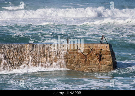 Starke Winde fahren Wellen über der Oberseite von der Mole in Sennen Cove, Cornwall, England. Großbritannien Wetter. Stockfoto