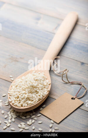 Haufen von weißem Reis in Holzlöffel auf Tisch mit Label für Text. Stockfoto