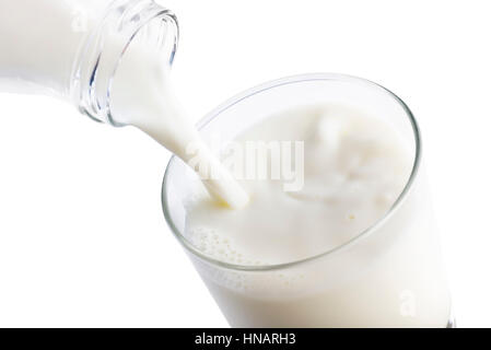 Gießen Milch in ein Glas von Flasche auf weißem Hintergrund Stockfoto