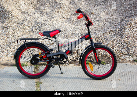 Kinder schwarz und rot Fahrrad auf einem Kies-Hintergrund Stockfoto