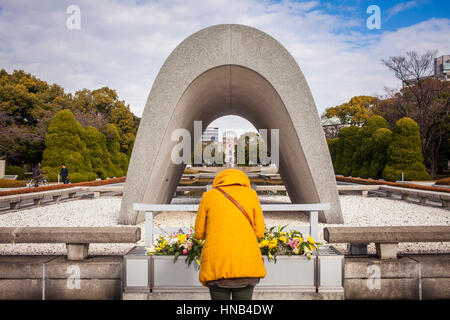 Beten, Kenotaph für den Atomic bomb Opfer, im Hintergrund Atomic Bomb Dome, Friedenspark, Hiroshima, Japan Stockfoto