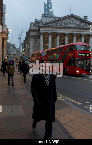 Ein besorgt aussehende Pendler geht vorbei an den Neo-römischen Säulen der Royal Exchange und Busse am 9. Februar 2017, in der City of London, England. Stockfoto