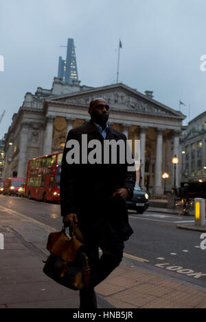 Eine schwarze Stadt Arbeitskraft geht vorbei an der Neo-römischen Säulen der Royal Exchange am 9. Februar 2017, in der City of London, England. Stockfoto