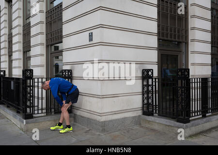 Außerhalb des Büros von BP erstreckt sich ein Geschäftsmann müde Beinmuskulatur auf 3. Februar 2017, in St James Square, London, England. Stockfoto