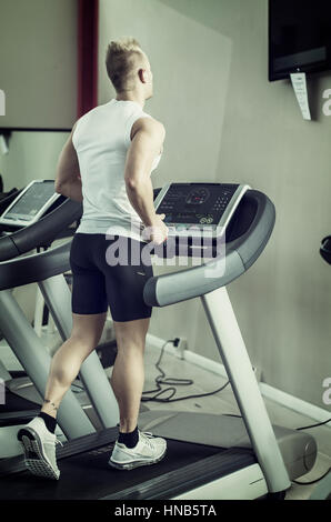 Blonden attraktiven jungen Mann auf Laufband, von hinten gesehen Stockfoto