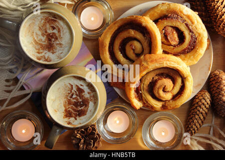 Sahne gekrönt gemütliches Kerzenlicht in einem englischen Haus im Winter serviert Kaffee und Zimt Strudel-Gebäck Stockfoto